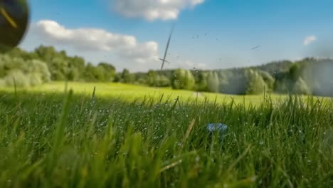 golf club hits a golf ball in a super slow motion. drops of morning dew and grass particles rise into the air after the impact.