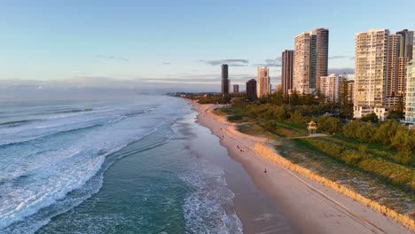 Drone captures Gold Coast's Broadbeach at sunrise, highlighting skyscrapers, ocean waves, and golden morning light