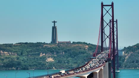 traffic at the 25 de abril bridge over the tagus river with the christ the king sanctuary in lisbon, portugal