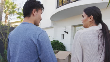 video of back view of diverse couple walking into new house