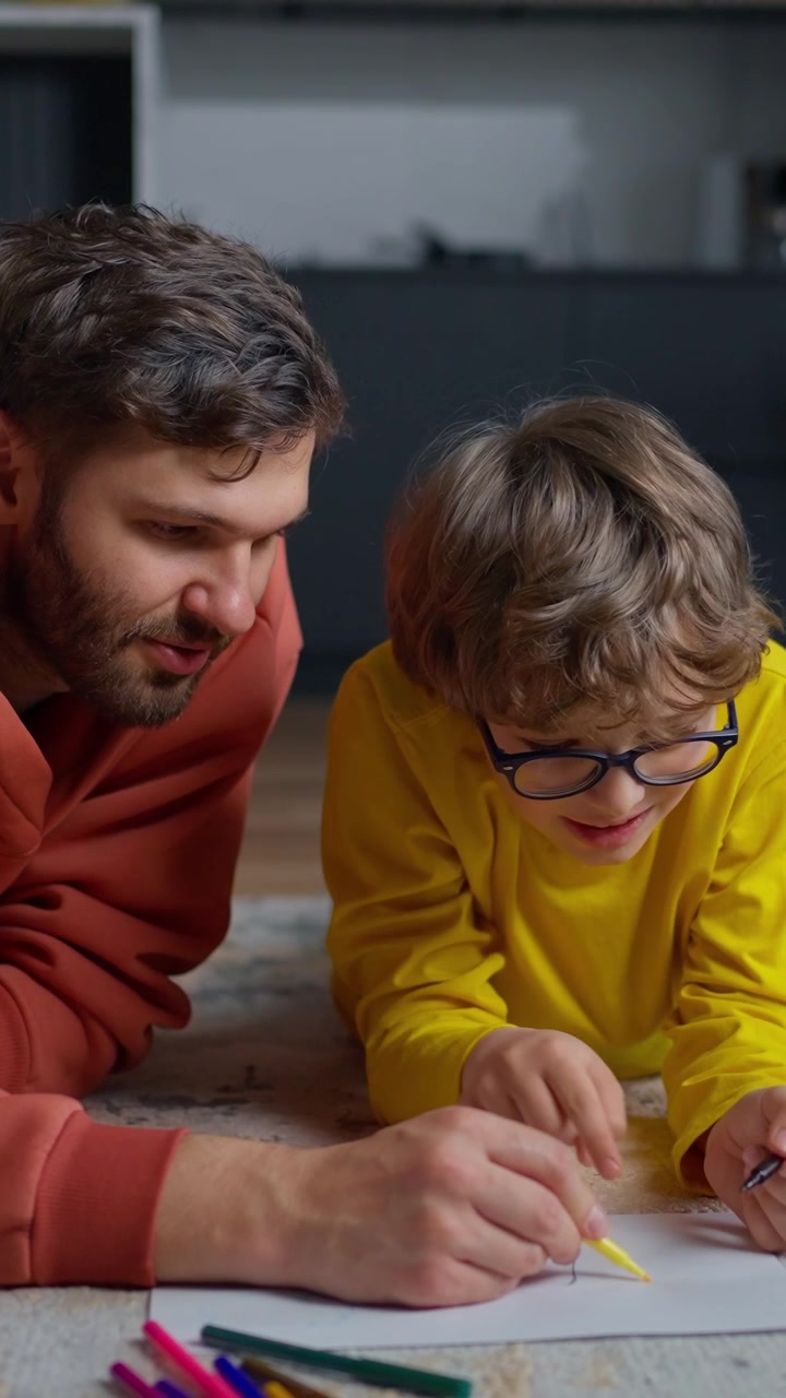 Padre e figlio disegnano insieme sul pavimento di casa