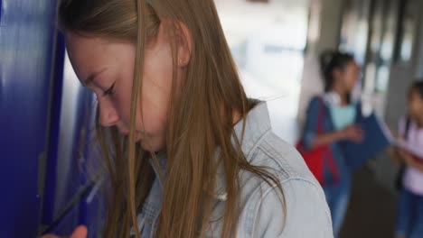 Video-of-sad-caucasian-girl-crying-by-lockers-in-school-corridor,-copy-space