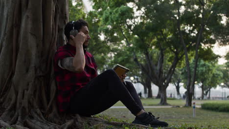 man relaxing in a park with headphones and a tablet