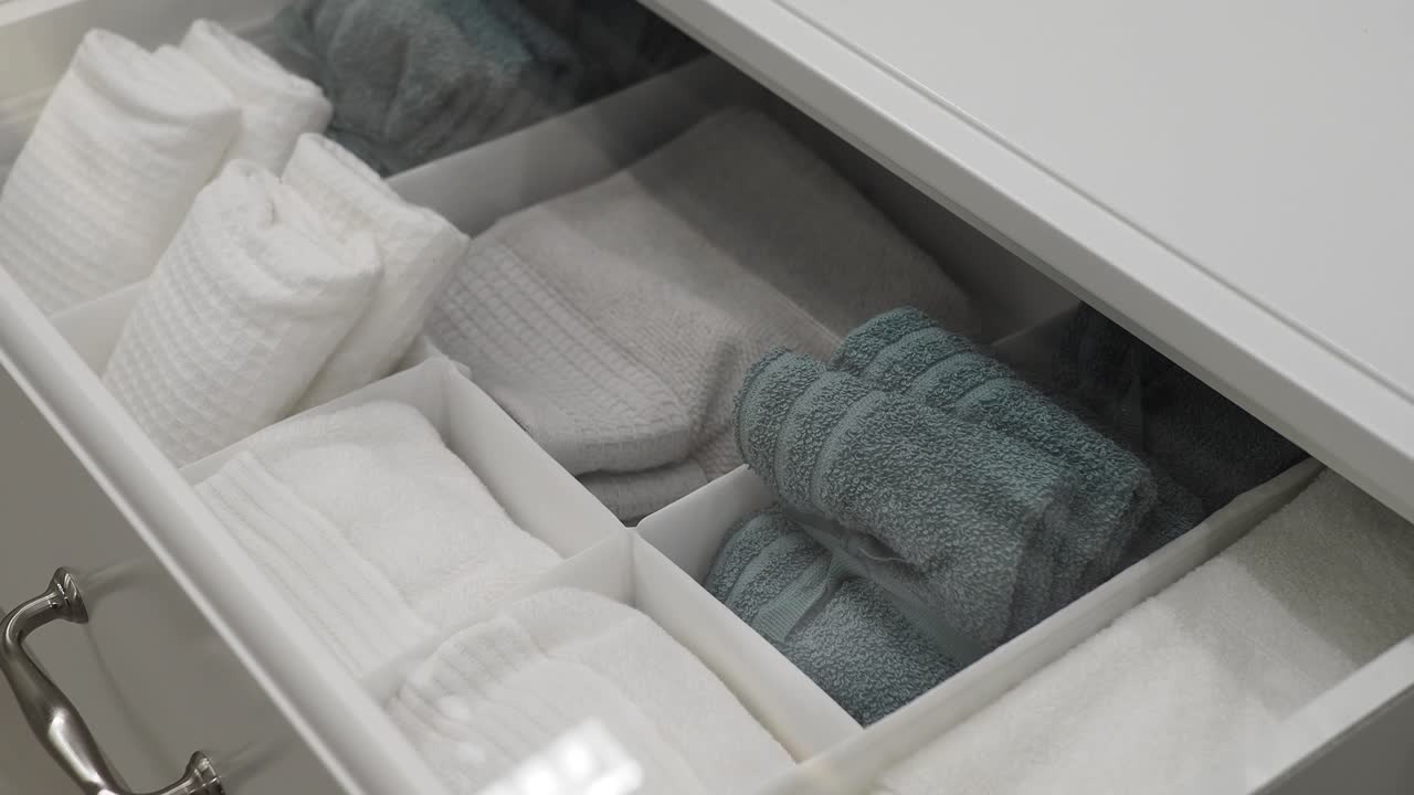 Organized bathroom drawer with white and green towels