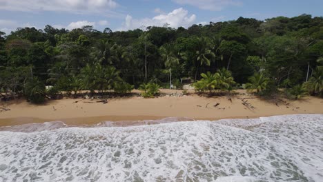 Aerial-view-of-tropical-beach-with-golden-sand-and-lush-green-forest-in-the-background,-waves-gently-crashing-on-the-shore-of-Playa-Buff-In-Bocas-del-Toro,-Panama