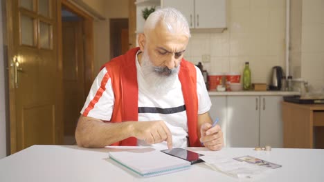 Man-calculates-at-home-with-calculator-and-looks-at-bills.