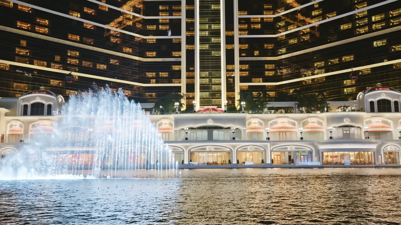 Edificio di lusso di un hotel illuminato con un grande spettacolo di fontane d'acqua di notte