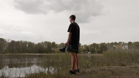 young man standing in nature holding gimbal with camera for filmmaking