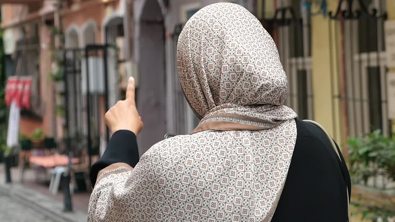 Woman wearing hijab pointing at street