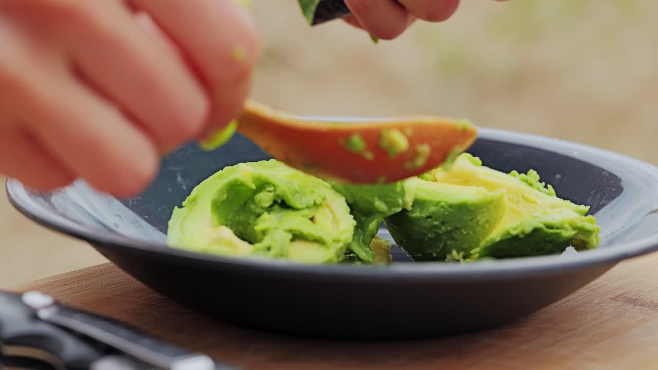 Bright nails contrast with green avocado as woman preps superfood in nature
