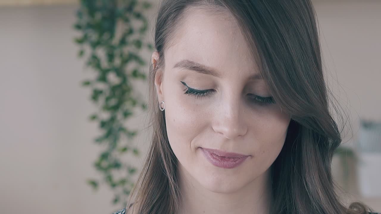 mujer feliz con cabello rubio y maquillaje ligero contra la pared