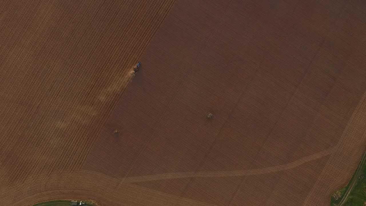 먼지가 많은 들판 조감도에서 트랙터와 파종기로 파종하는 들판