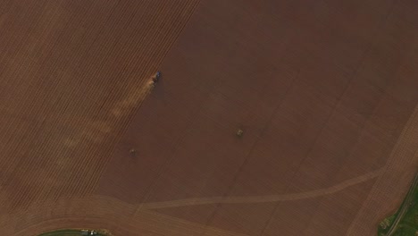 Sowing-fields-with-tractor-and-seeder-in-dusty-field-aerial-view