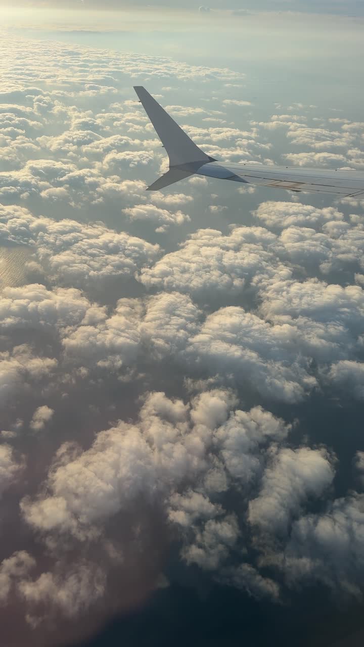 Ala di un aereo in volo sopra nuvole soffici durante l'ora d'oro.