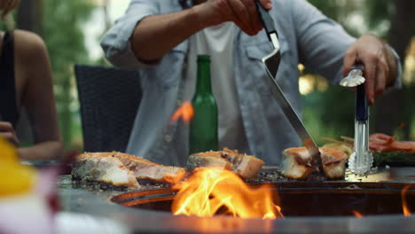 Unrecognizable-guy-preparing-bbq-fish-outside