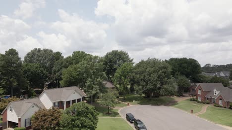 a drone zoom in shot capturing a suburban neighborhood in the united states showcasing tree-lined streets and residential houses. the greenery and -planned layout highlight the peaceful suburban