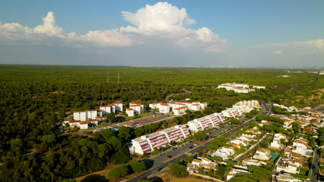 Toma-Aérea-De-La-Ciudad-De-El-Rompido-Con-Bloques-De-Apartamentos-Frente-A-Bosques-Verdes-En-España