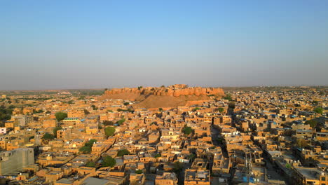 tomada lateral de un dron del fuerte de jaisalmer, que muestra su majestuosa belleza rodeada de casas de tonos dorados en un día soleado de rajasthan, india 4k
