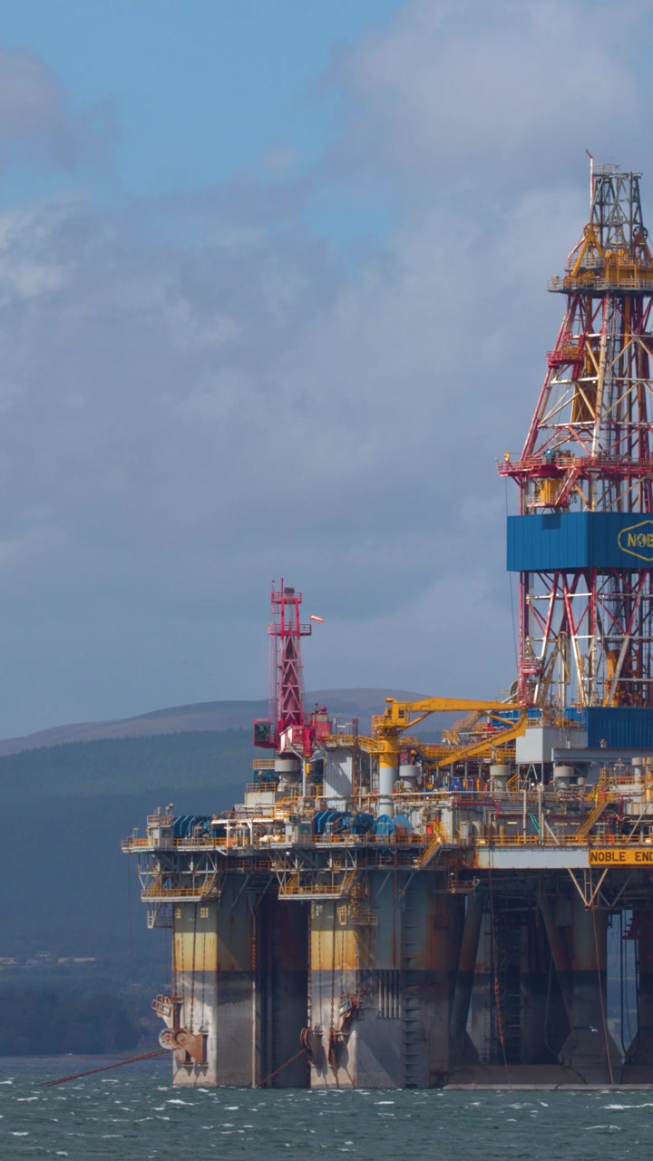 Stor offshore olieboreplatform stationær i Cromarty Bay, dagslys, vidvinkelbillede, roligt maritimt miljø.