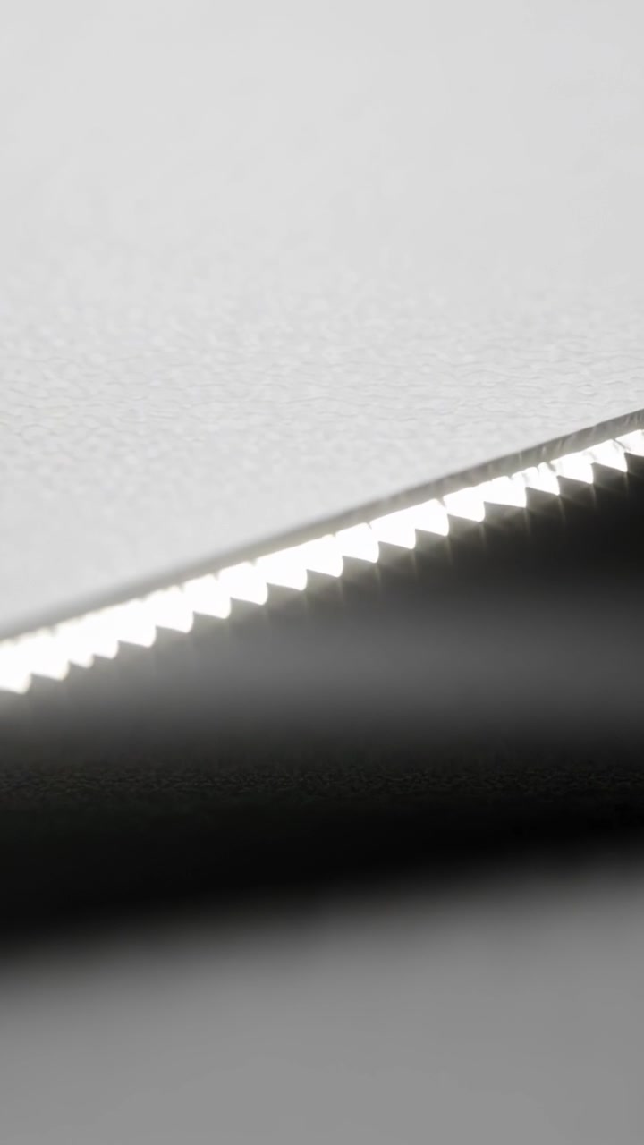 Vertical video: Shifting camera focus sharpening serrated metal edge on bench, with dark cylinder