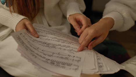 two girls study music score books, pointing out details with fingers