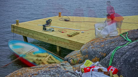 Static-shot-over-a-worker-cottecting-unused-wood-in-timelapse-over-a-small-boat-after-constructing-along-the-lakeside-at-daytime