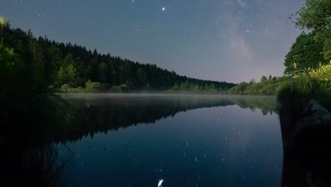 cinematic slide up of the moving milkyway at a star clear night with it's refection in a little lake