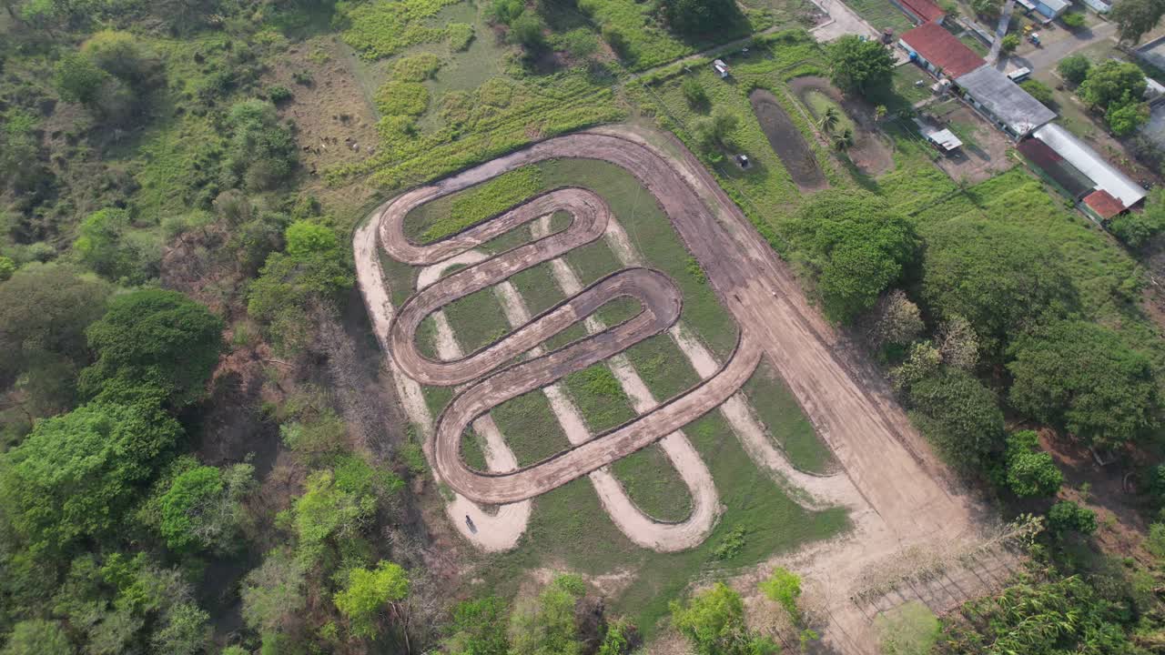An empty motocross racetrack, showcasing curved tracks in open space, aerial view