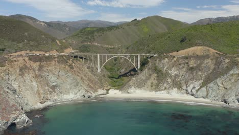 drone vuela directamente hacia el puente bixby creek sobre el océano pacífico, montañas en segundo plano