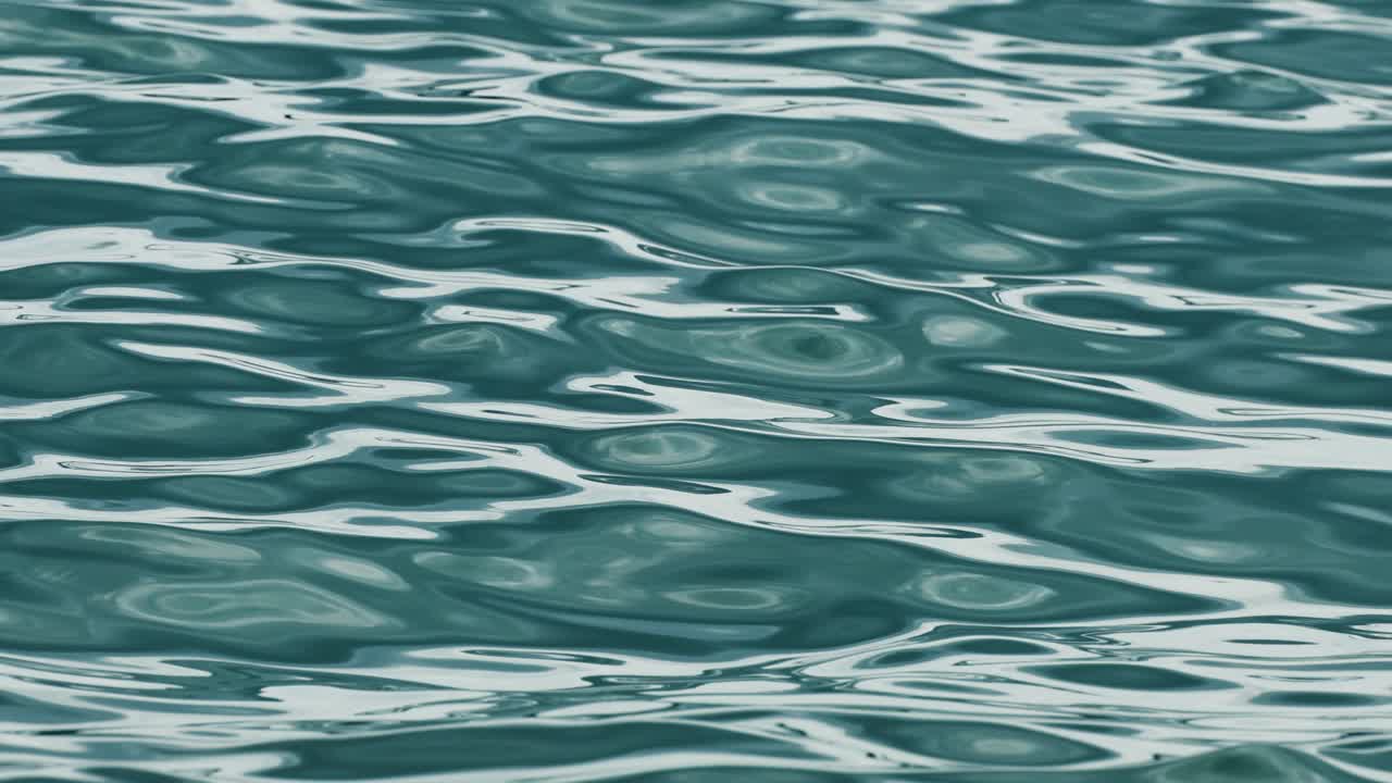 Calm ocean waves ripple softly under natural light in Phuket, Thailand. The camera captures the serene movement of water