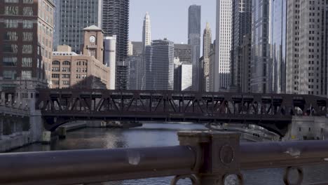 Subway-and-cars-riding-over-steel-Bridge-in-Chicago,-skyline-on-sunny-day
