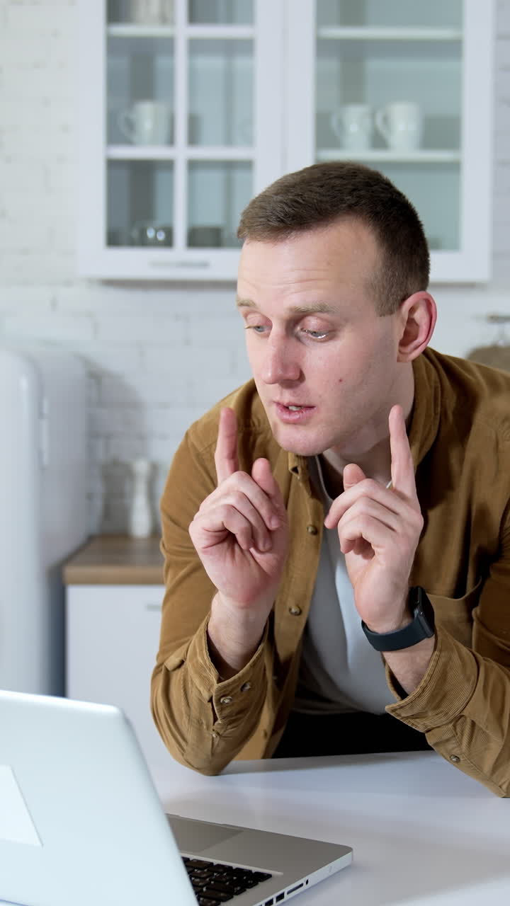 Young fellow having a video call at home. Distant job. Man is talking to a client through the laptop. Remote education. Vertical video