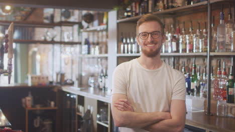 portrait of smiling male bar worker standing behind counter