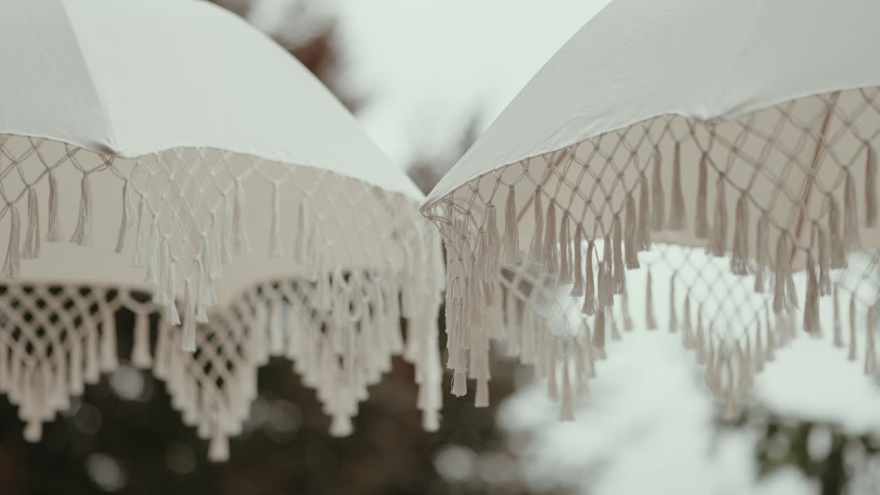 Closeup of white umbrellas with hanging tassel details