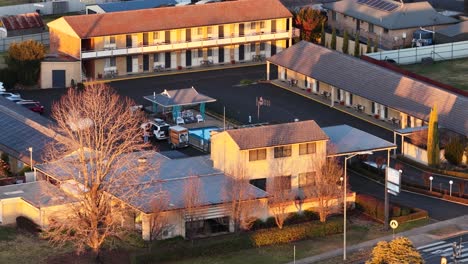 aerial camera smoothly pans over a motel complex and empty street in coonabarabran, australia, bathed in warm sunset light with visible smoke haze
