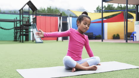 en un patio de juegos de la escuela, una joven afroamericana practica yoga
