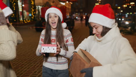 friends opening christmas presents on the street at night