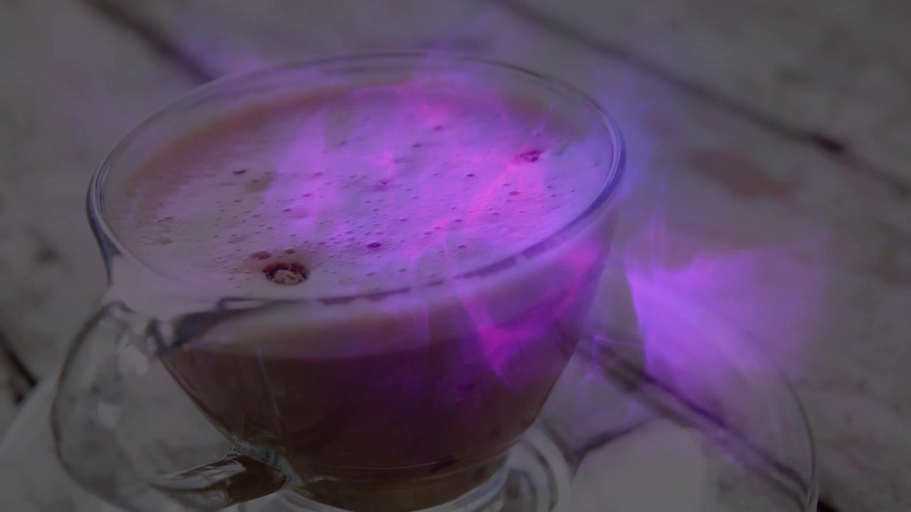 All'inizio, una foschia viola si forma, pulsando e fluttuando attorno a una tazza di vetro, creando un'atmosfera magica.