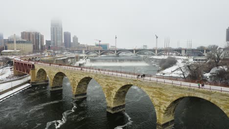 people walking on stone arch bridge in minneapolis, minnesota on foggy winter morning