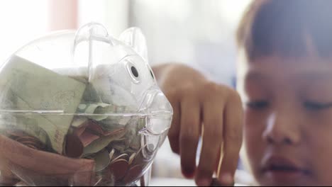 el niño está recogiendo monedas para dejar caer la alcancía.