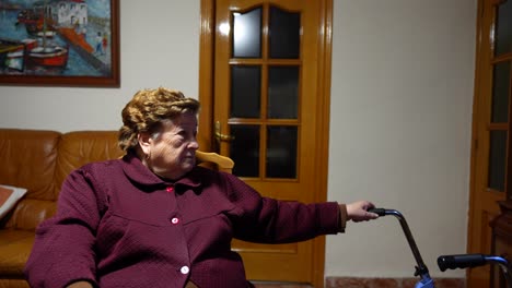 granny seated with a walker watching tv at home alone