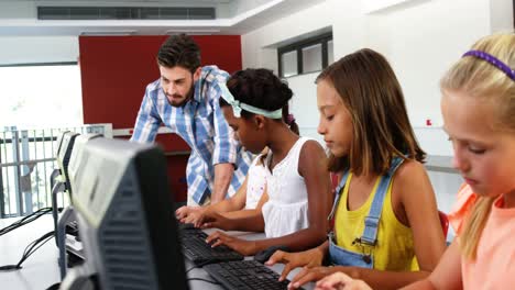 teacher assisting schoolgirls in learning computer