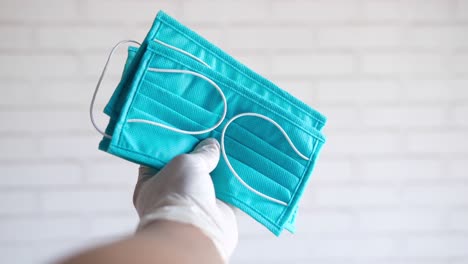 hand with gloves holding blue face masks