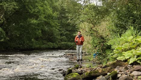 hand-held shot of a flyfisherman walking and casting into a small stream