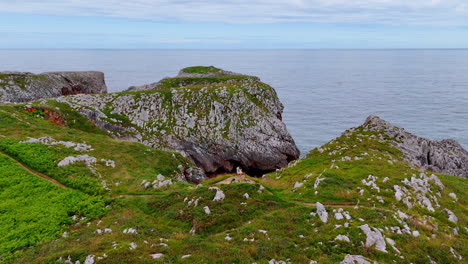 couple stands at the precipice over the seascape. drone footage above the rocky shore of spain, europe.