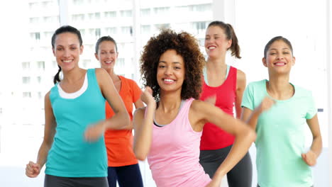 pretty instructor leading zumba class in fitness studio