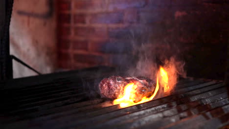 el chef de barbacoa levanta el bistec en la parrilla y produce llamas.