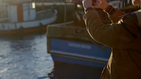 Woman-clicking-photos-with-mobile-phone-at-dock-4k