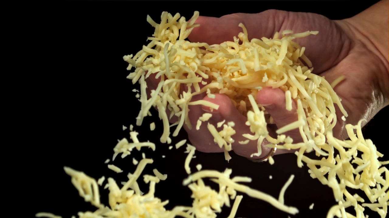Formaggio grattugiato che cade dalla mano al rallentatore