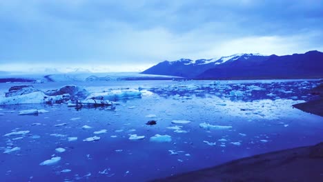 Stunning-drone-aerial-over-icebergs-in-a-glacial-bay-suggest-global-warming-in-the-Arctic-at-Jokulsarlon-glacier-lagoon-Iceland-night